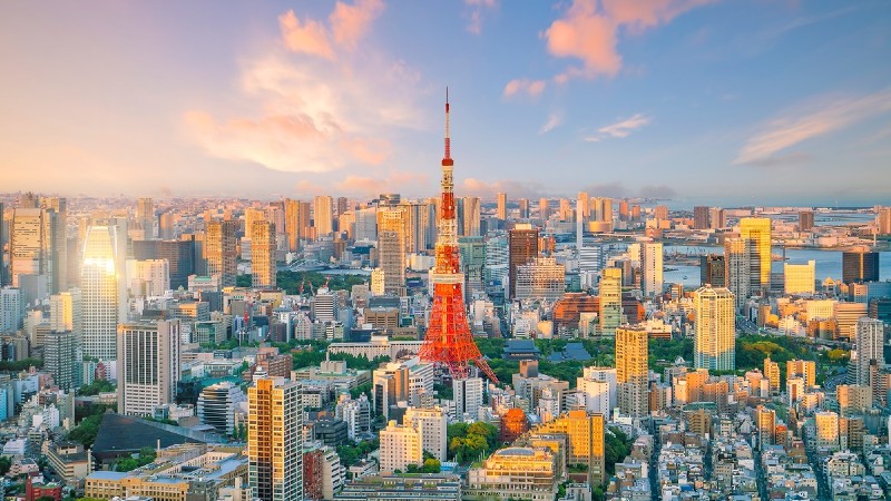 Aerial view of Tokyo, Japan, with a tall red and white tower surrounded by city buildings at sunset.