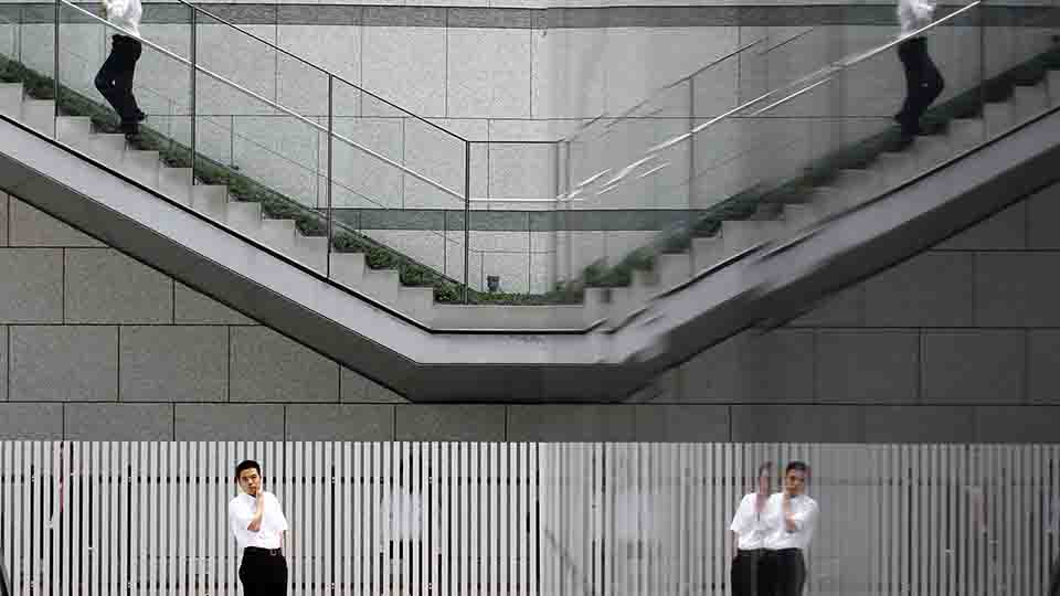 Businessmen are reflected on walls at a business district in Tokyo September 14, 2010.