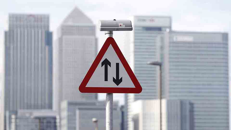 A traffic sign is pictured in front of the skyline of the the Canary Wharf financial district in London October 21, 2010.