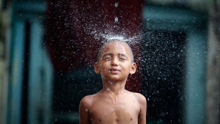 Buddhist novice monk Kyaw Thiha plays during heavy rainfall at Shin Ohtama Tharya monastery in Yangon May 31, 2011.