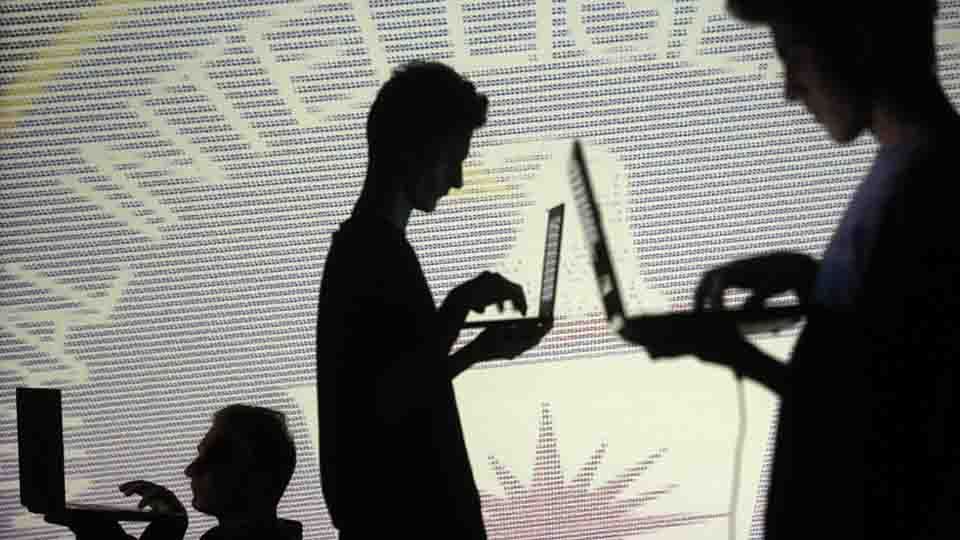 People are silhouetted as they pose with laptops in front of a screen projected with binary code and a Central Inteligence Agency (CIA) emblem, in this picture illustration taken in Zenica October 29, 2014.