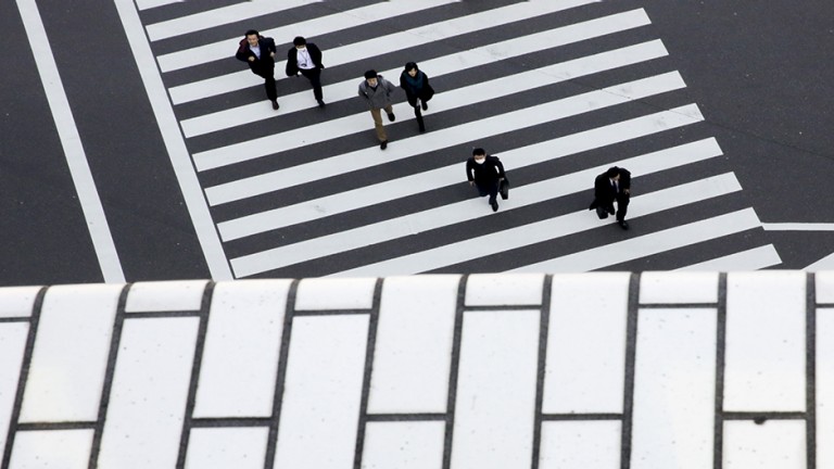 People cross a street in a business district in Tokyo, Japan, February 16, 2016