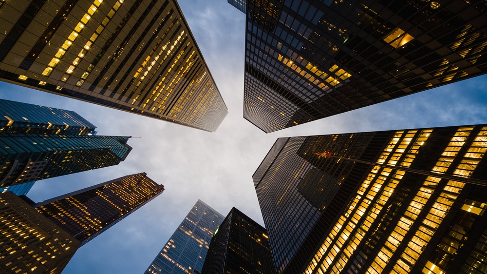 空を背景に見上げた近代的なオフィスビル群。企業ガバナンスと法的リスク管理を象徴しています。